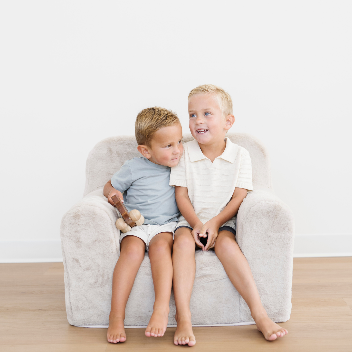 Brothers sit next to each other in a soft cozy faux fur chair for kids.
