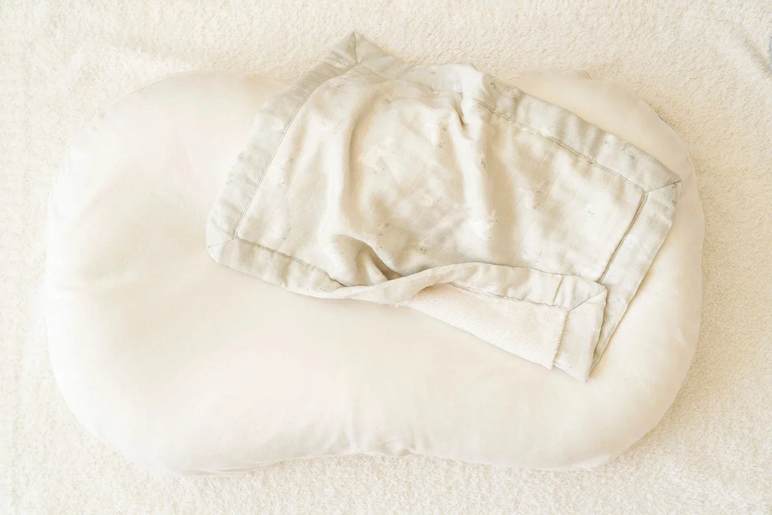 A burgundy blanket with cream constellation embroidery lies on a white surface with one corner folded to reveal its cream-colored underside.