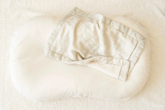 A burgundy blanket with cream constellation embroidery lies on a white surface with one corner folded to reveal its cream-colored underside.