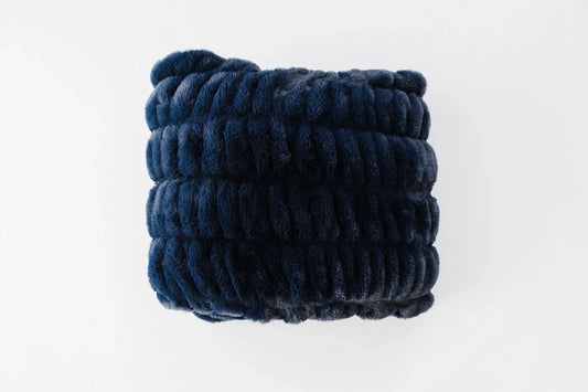 A folded navy Lush blanket photographed in studio light, showing the cloud-like ribbed texture and generous weight — a Father's Day throw for the nursery glider.