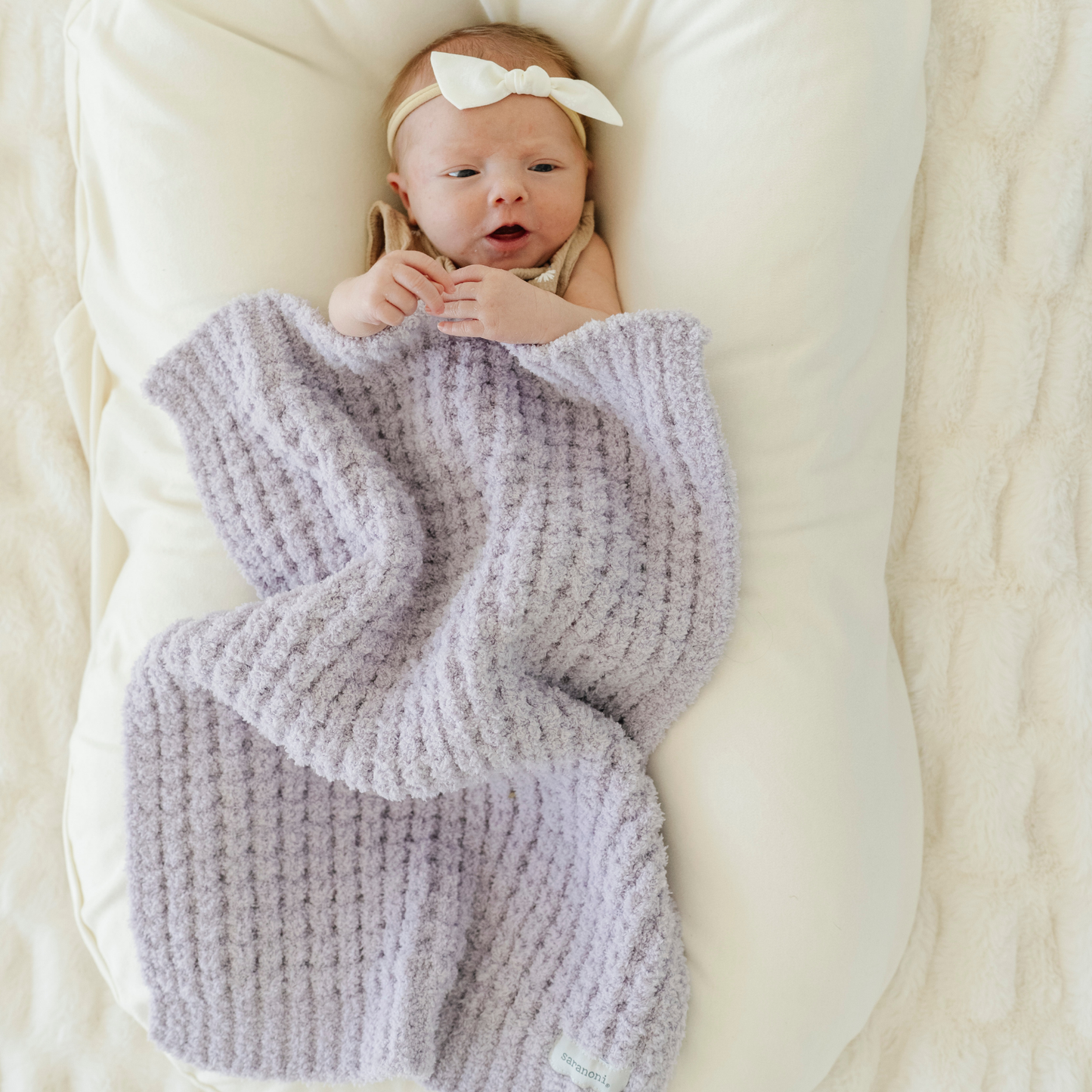 Baby girl snuggled with Wisteria Waffle Knit mini baby blanket. 