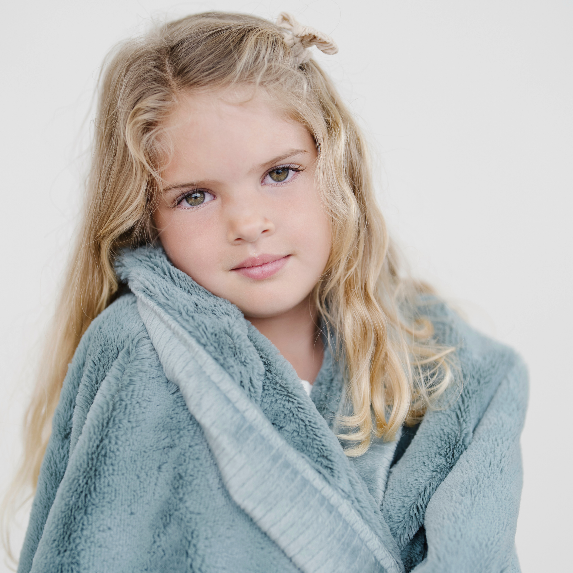 Girl wrapped in eucalyptus lush toddler blanket.