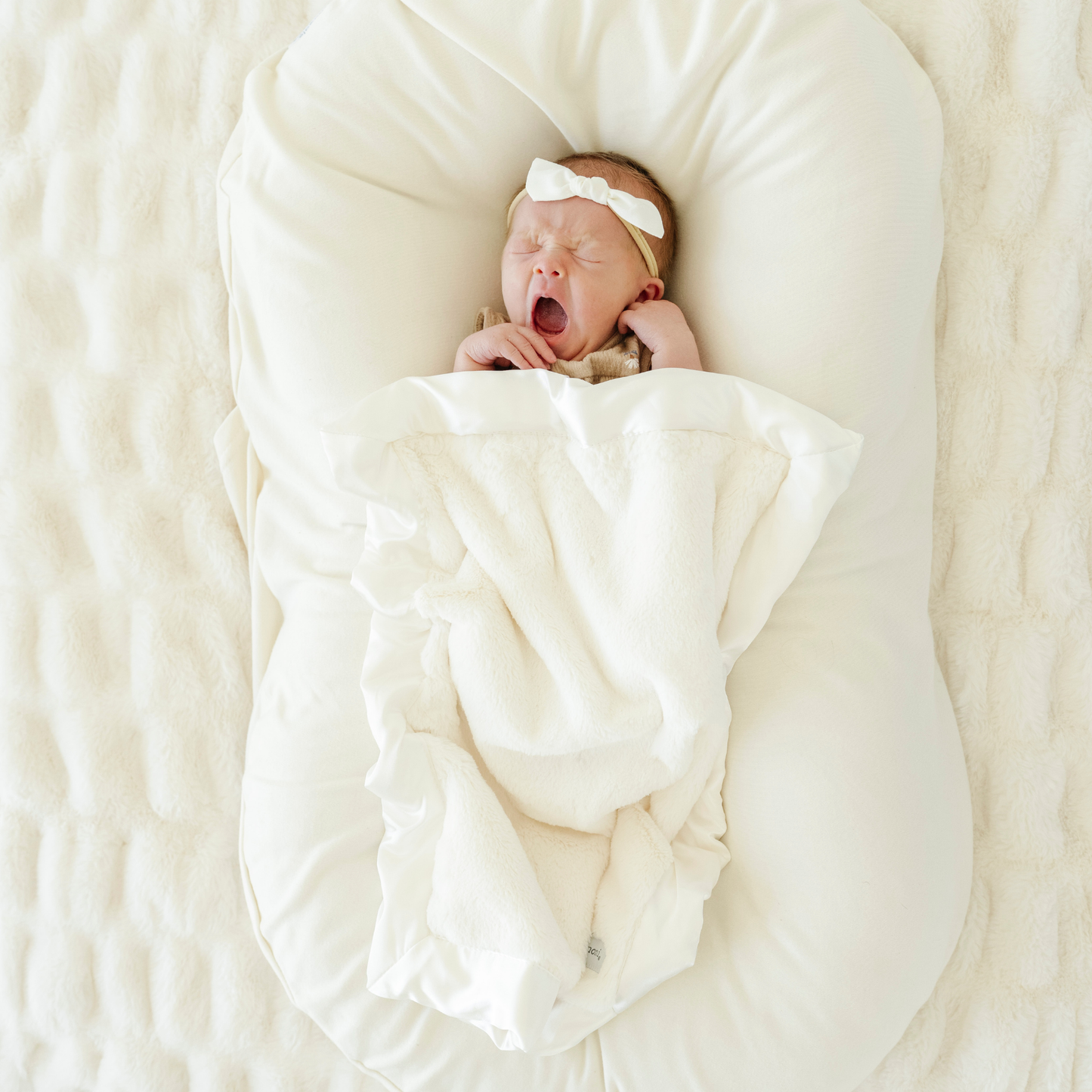 Baby girl snuggled with Ivory Satin border Mini baby blanket. 