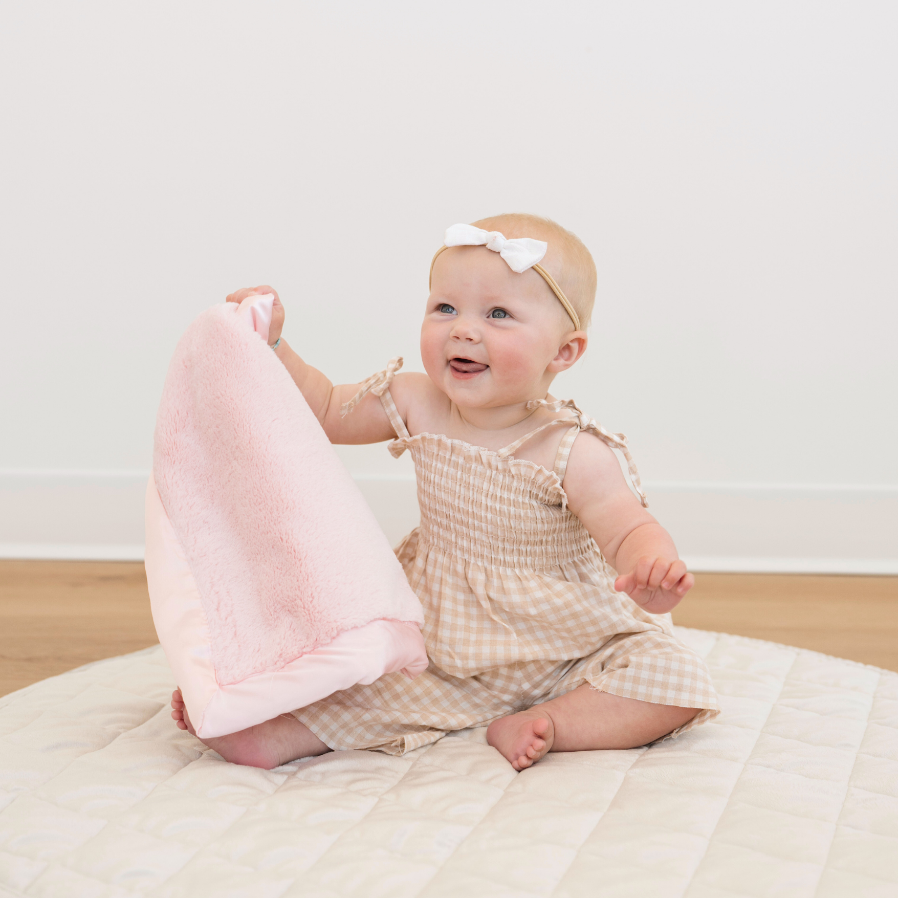 Baby girl holding Light Pink Satin border mini baby blanket. 