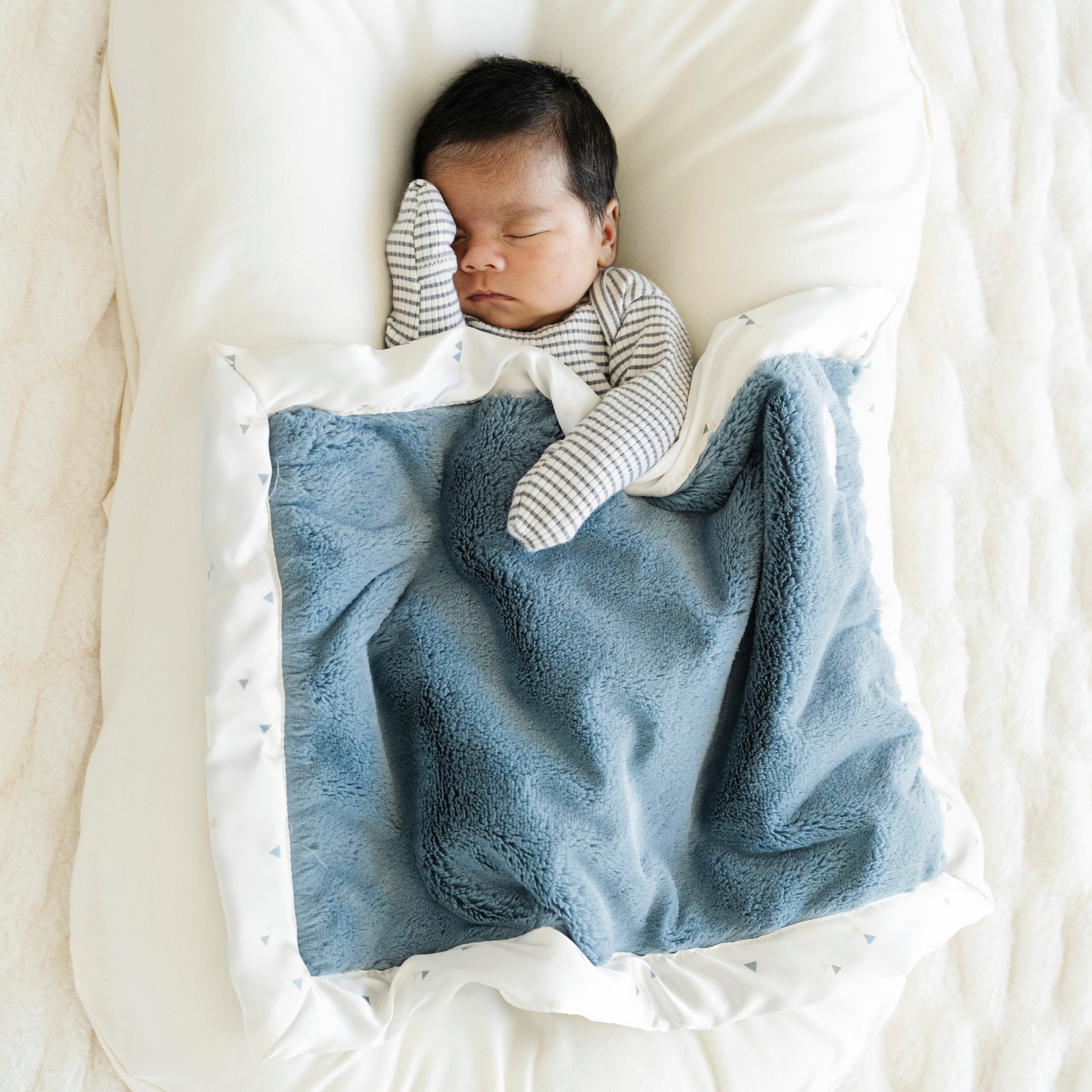 Baby Boy snuggled in Satin Border Mini baby blanket in Sea Glass print. 