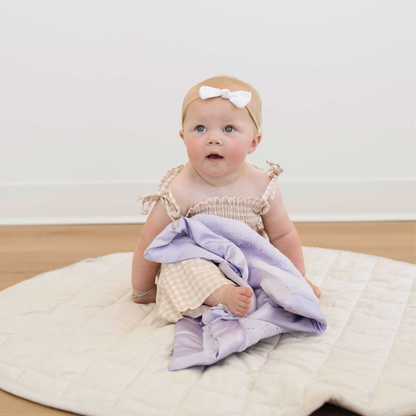 Baby girl snuggled with Saranoni satin soft mini blanket in Lavender. 
