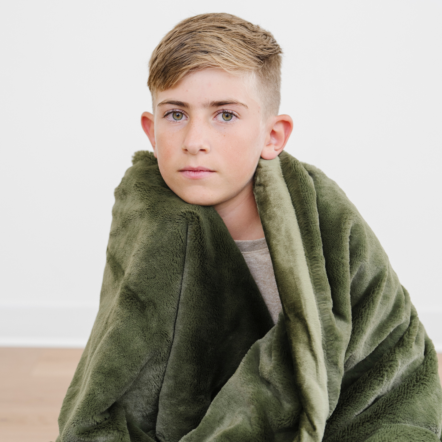 Boy wrapped in fern green lush toddler blanket. 