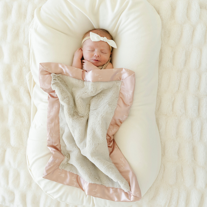 Baby girl snuggled with Dainty Floral Satin Back Mini baby blanket. 