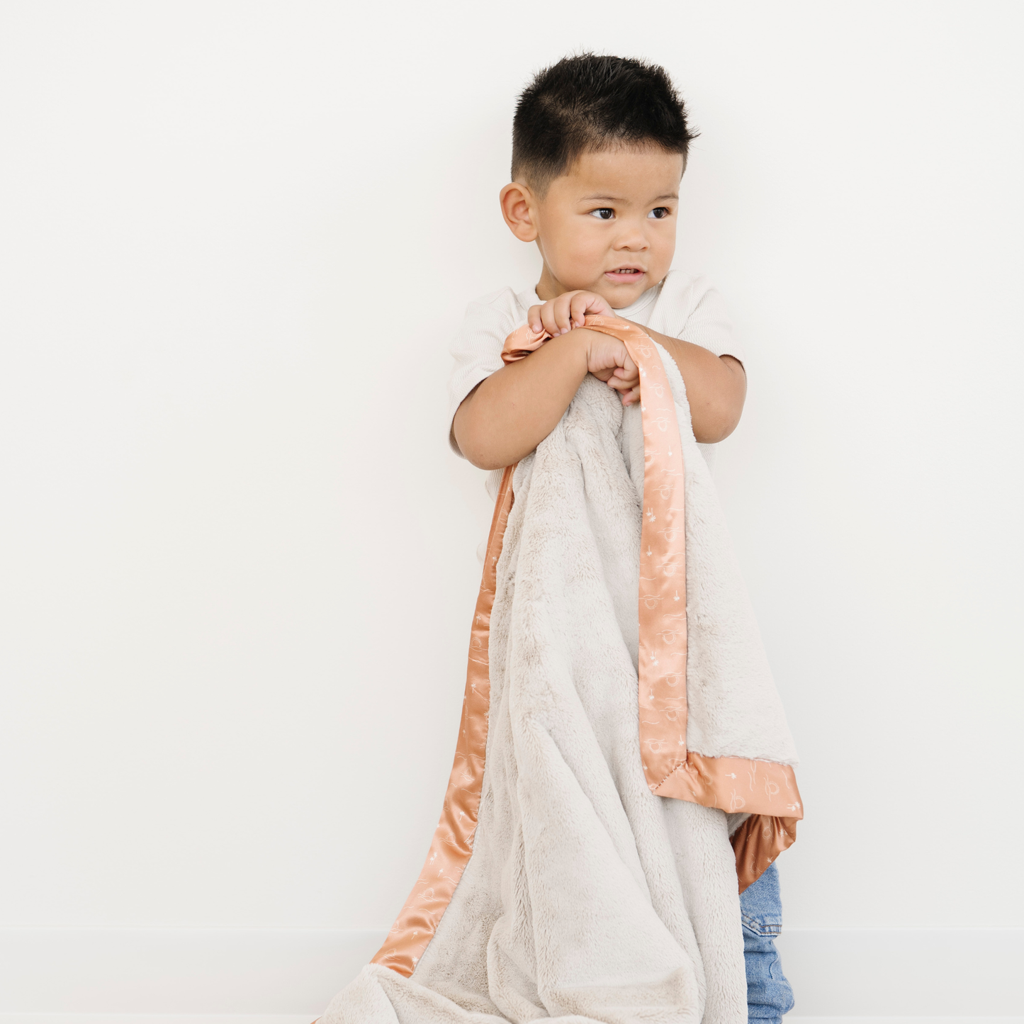 Toddler boy snuggled with Lush toddler blanket with a satin border in Sun & Sea print. 