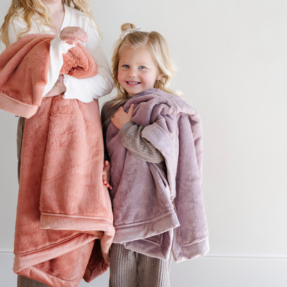 A little girl holds a Luxury Receiving Bloom (dusty purple) Colored Lush Saranoni Blanket. The soft blanket is a small blanket and a baby blanket or toddler blanket.
