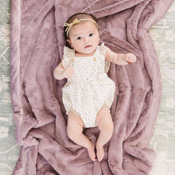 Bloom@A cute baby lays on her pink faux fur Saranoni blanket.