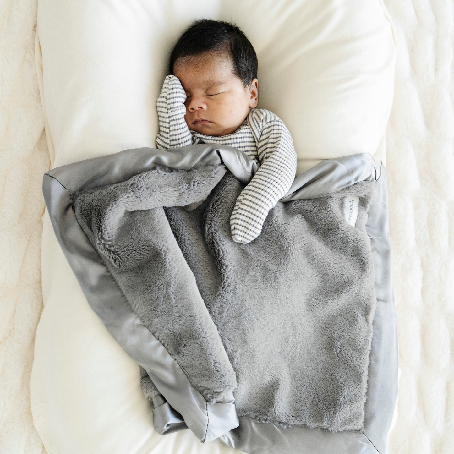 Baby boy snuggled in Gray Satin border mini baby blanket. 