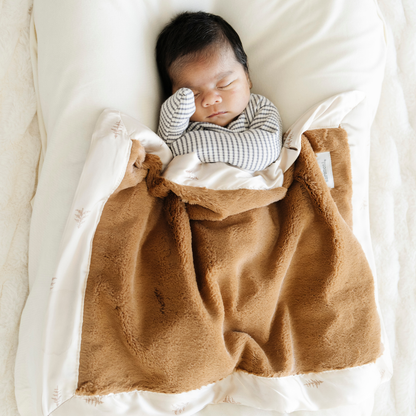 Baby boy snuggled with Saranoni soft Satin Back Mini baby blanket in Cedar print. 