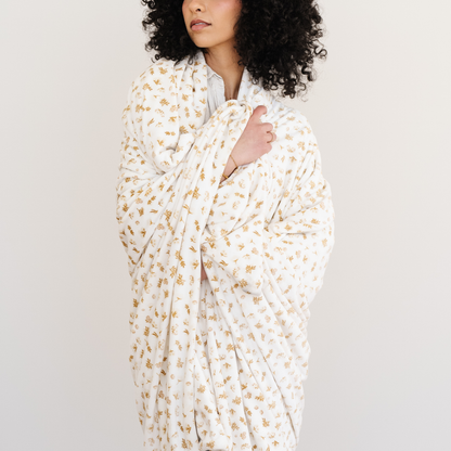 Woman wrapped in a floral printed blanket in the minky stretch fabric. 