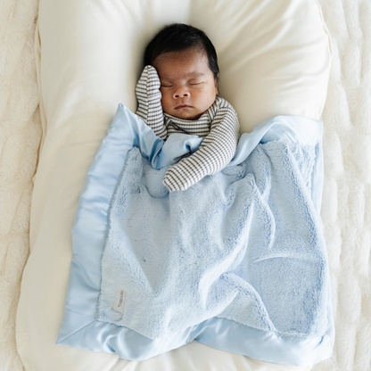 Baby boy snuggled in Light Blue satin border mini blanket. 