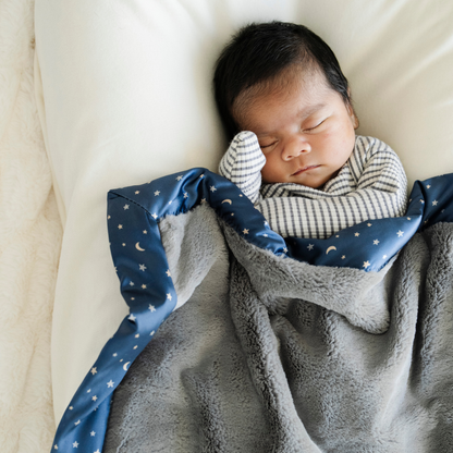 Baby boy snuggled in Twinkle Star Satin Border Mini baby blanket. 