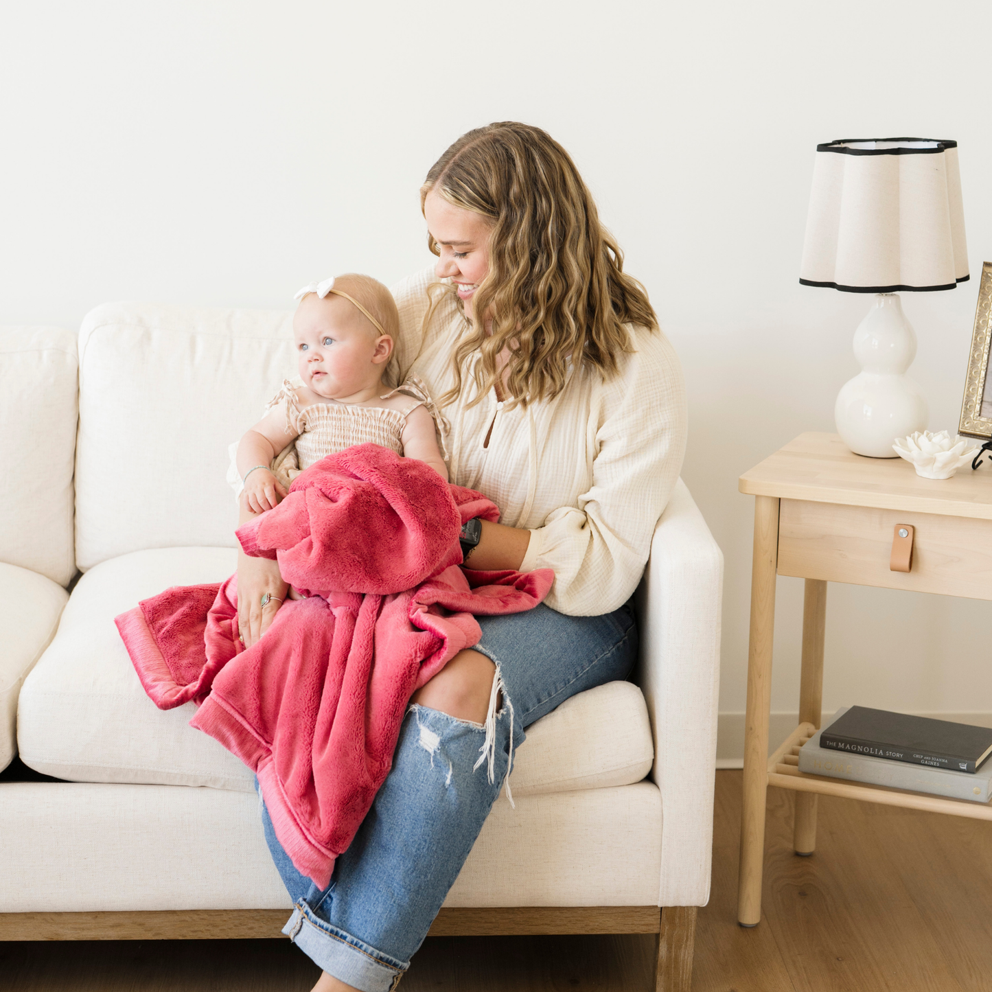 Mom sitting with baby girl snuggled with Saranoni lush receiving baby blanket in Primrose pink. 