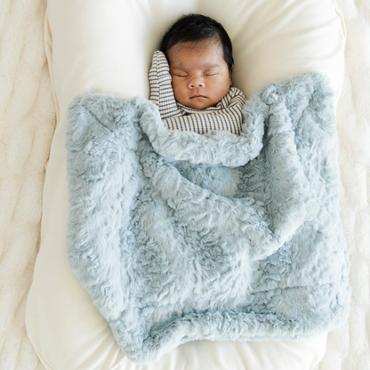 Baby boy snuggled with Heather Blue Dream Mini Baby Blanket.