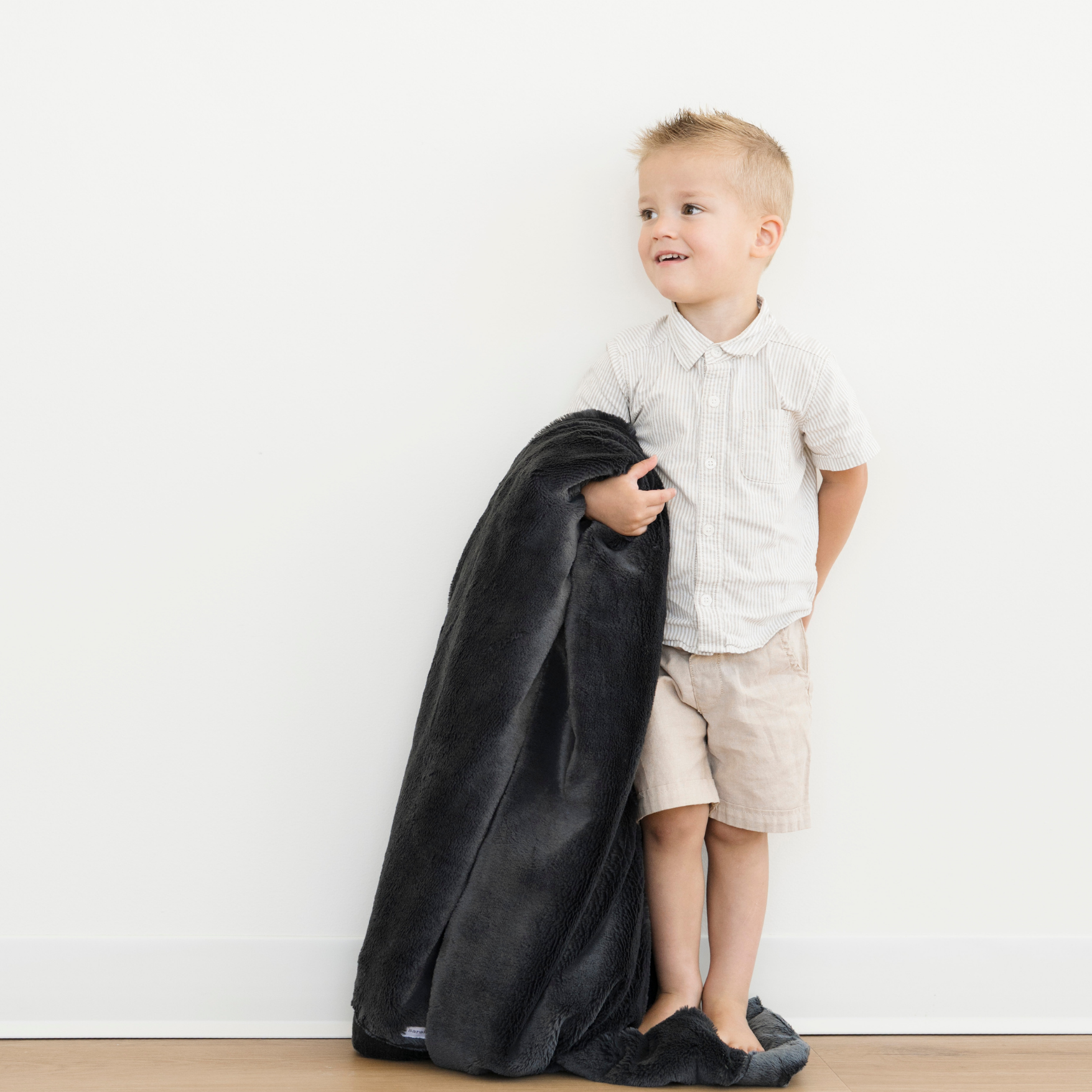 Toddler boy holding a Lush Toddler soft blanket in Charcoal color. 