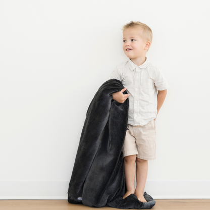 Toddler boy holding a Lush Toddler soft blanket in Charcoal color. 