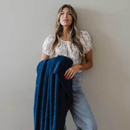 Woman stands holding nautical blue bamboni extra large blanket.