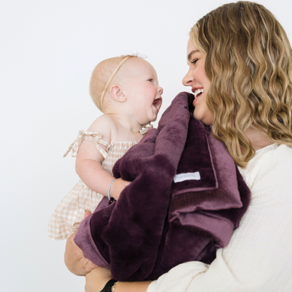 Mom holding baby girl snuggled with a soft lush receiving baby blanket in Aubergine purple. 