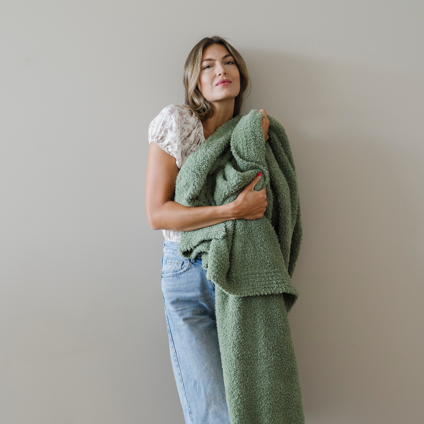 Woman wrapped in olive green cozy extra large bamboni blanket.