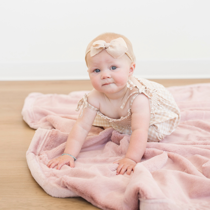 Baby girl crawling on Saranoni Lush Receiving soft baby blanket in Ballet Slipper pink color. 