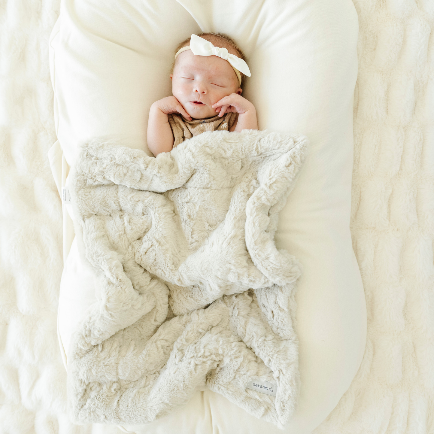 Baby girl snuggled with Oat Dream Mini baby blanket.