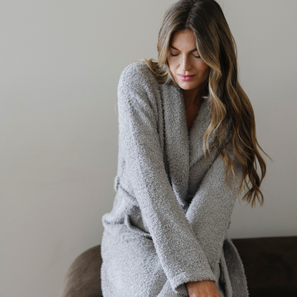 Woman snuggled wearing a gray bamboni cozy luxury robe. 