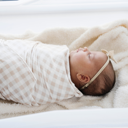 Newborn baby girl swaddles in gingham minky stretch luxe swaddle baby blanket. 
