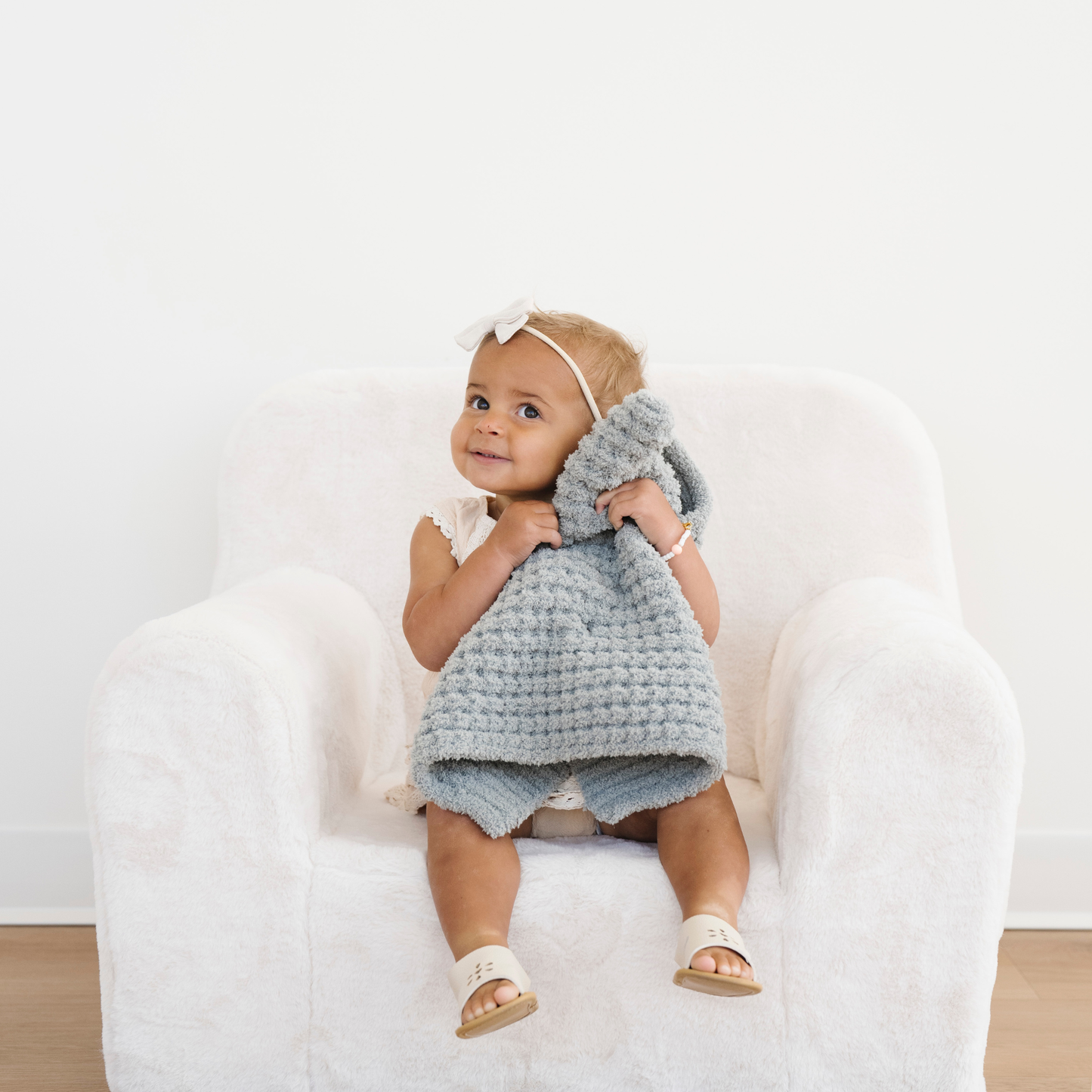 Toddler girl holds a elm green waffle knit mini blanket snuggled to her.