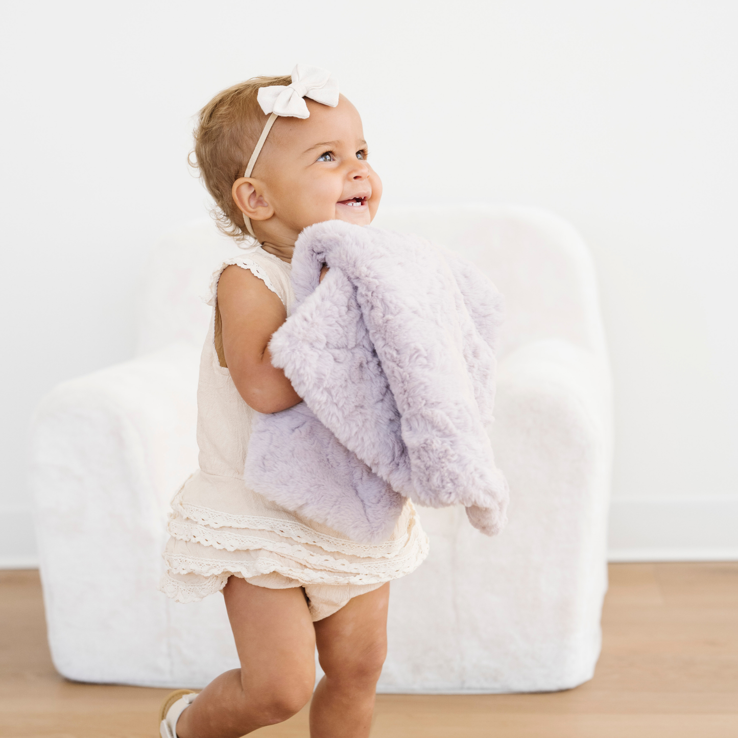 Toddler girl holding a purple dream faux fur mini baby blanket. 