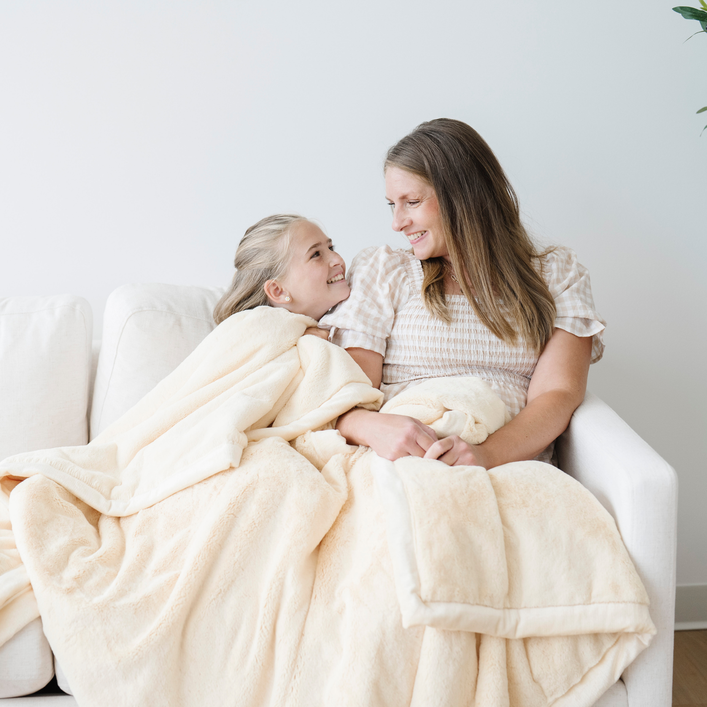 Mom and daughter snuggled on couch with chiffon yellow lush xl blanket.