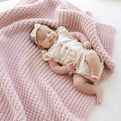 Baby girl sleeping on a pink waffle knit receiving baby blanket. 