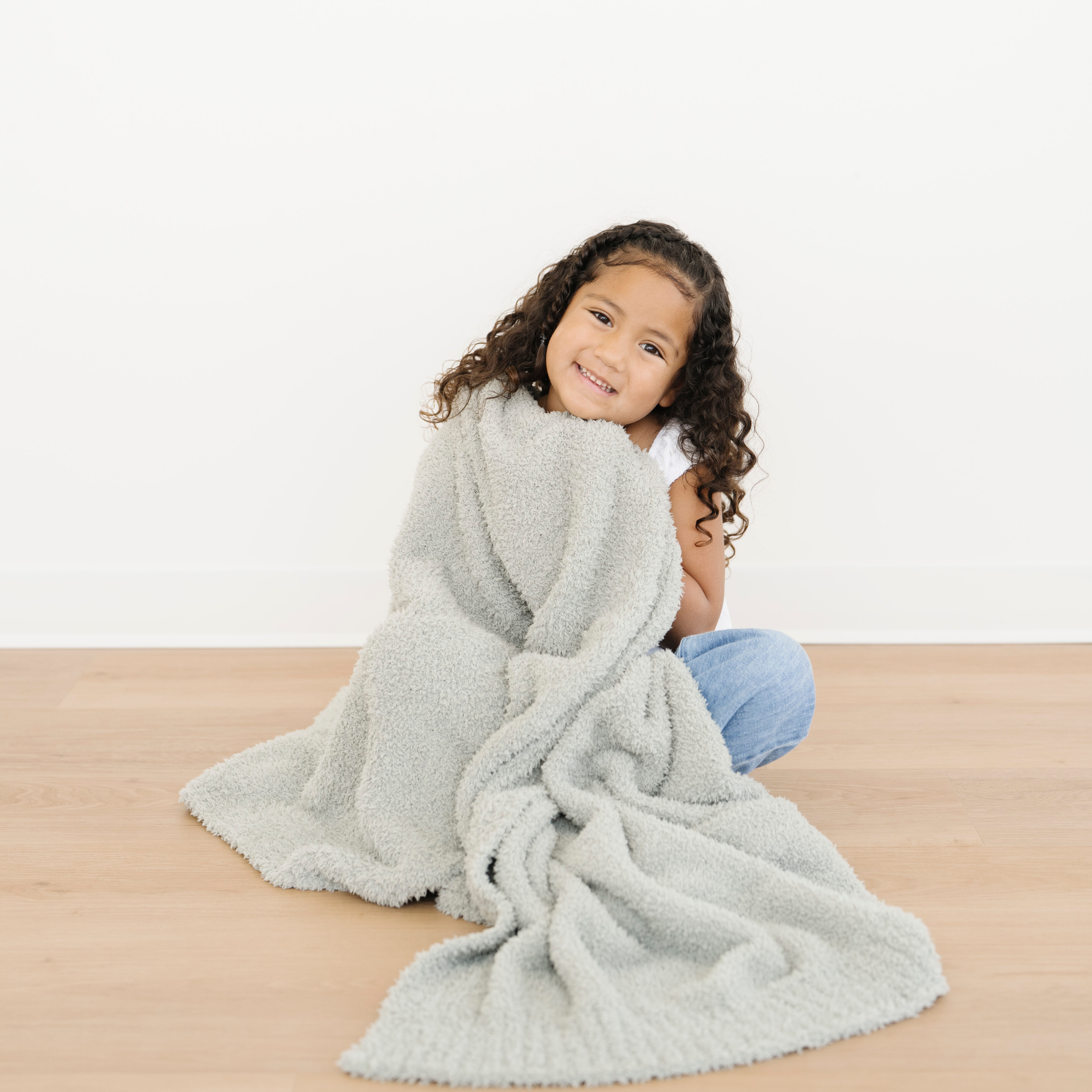 Girl snuggled with Saranoni oversized Bamboni® Toddler blanket in Sage green color. 
