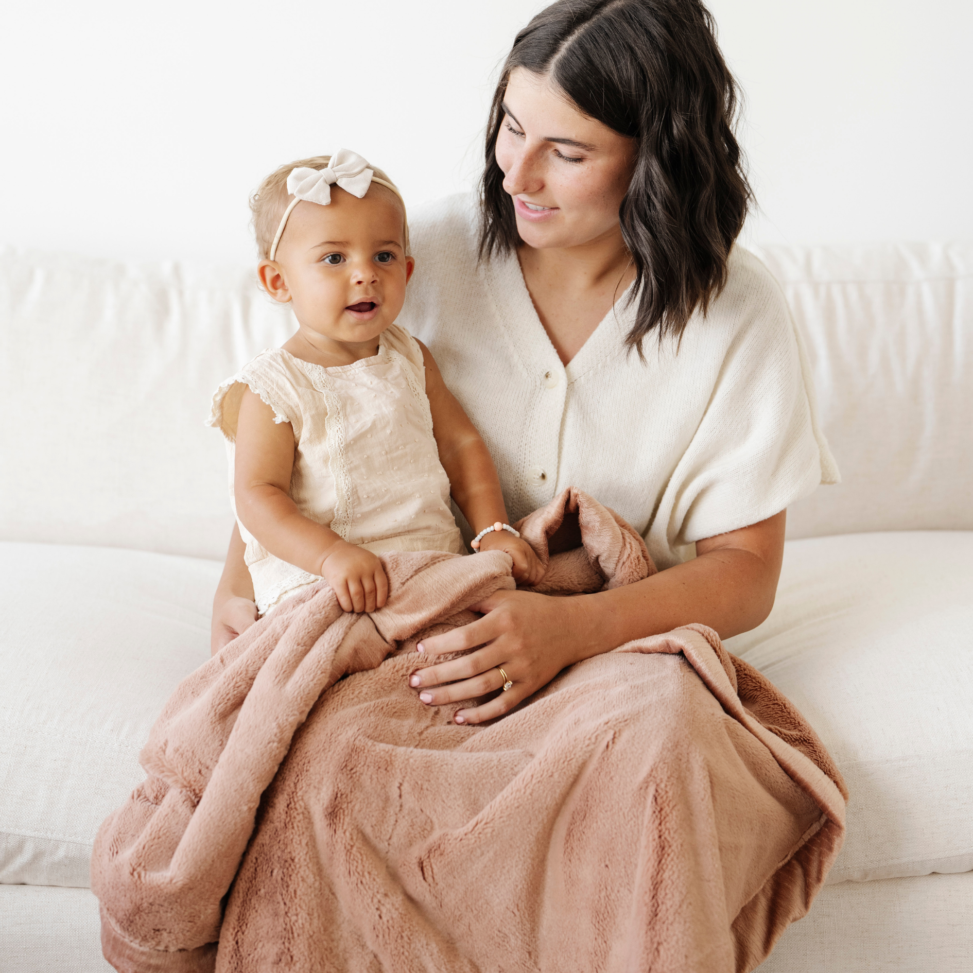 Mom holds little girl snuggled with a rosy pink lush receiving soft baby blanket. 