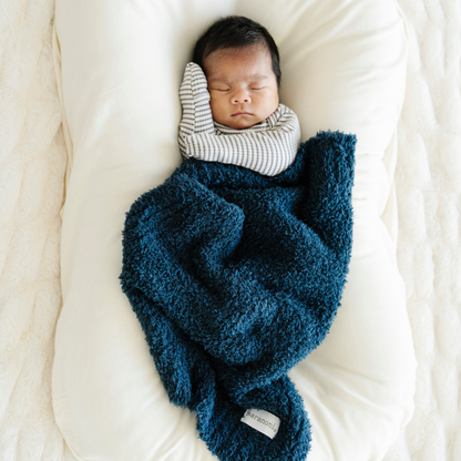 Baby boy snuggled in Saranoni Mini Bamboni® Baby blanket in Nautical blue. 