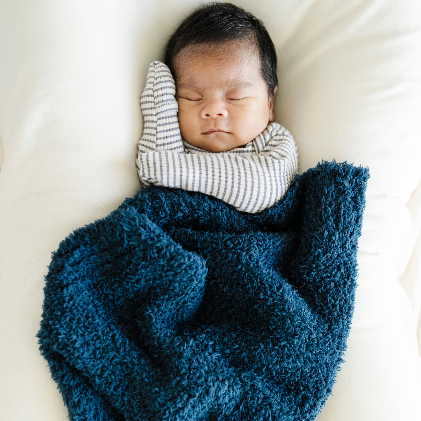 Baby boy snuggled with Nautical Blue Saranoni Bamboni® Mini baby blanket. 