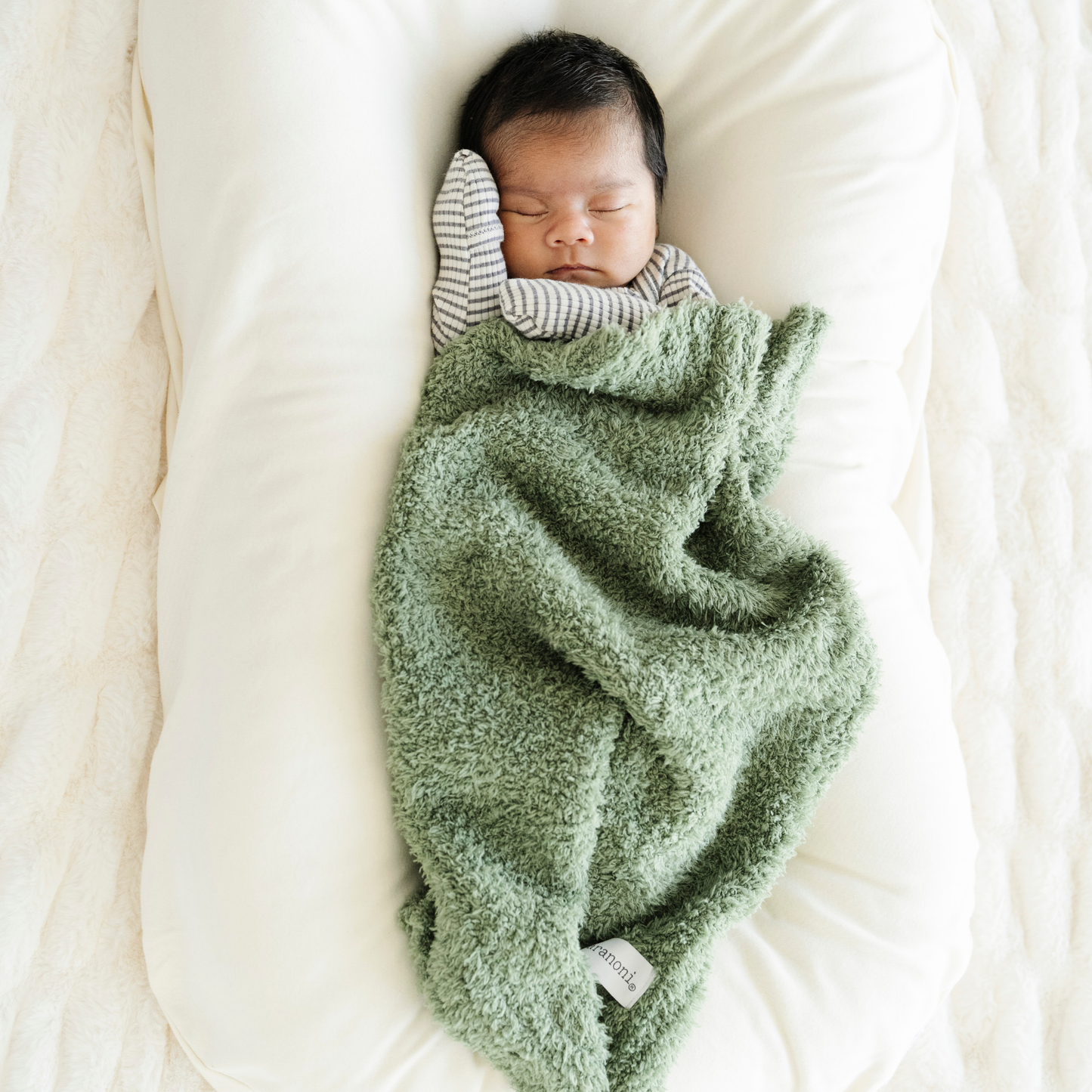 Baby boy snuggled with Saranoni Bamboni® mini baby blanket in Olive green color. 