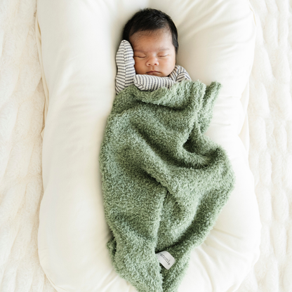 Baby boy snuggled with Saranoni Bamboni® mini baby blanket in Olive green color. 