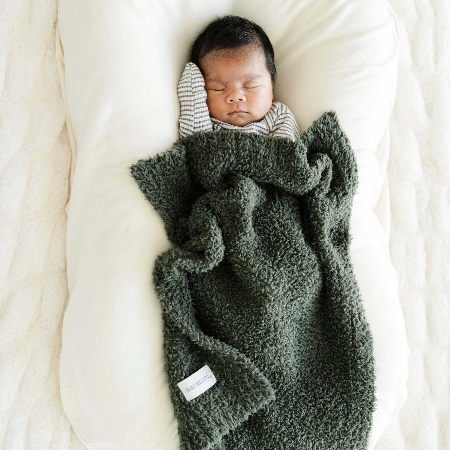 Baby boy snuggled in Juniper Bamboni® mini blanket. 