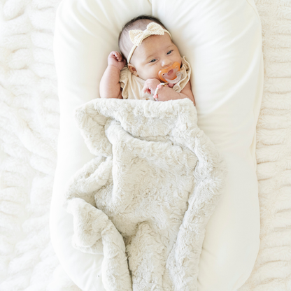 Baby girl wrapped in an oat tan dream faux fur mini blanket. 