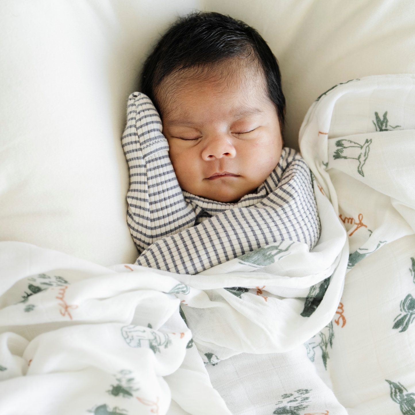 Baby boy with Bamboo Rayon Muslin Saranoni swaddle in Lakewood Animals print.
