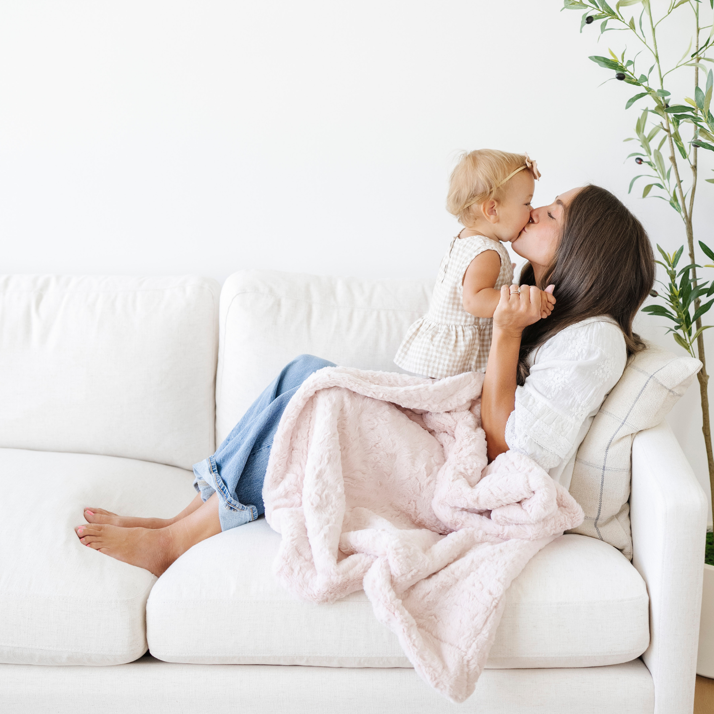 Mom snuggles baby girl with a pink soft receiving baby blanket. 
