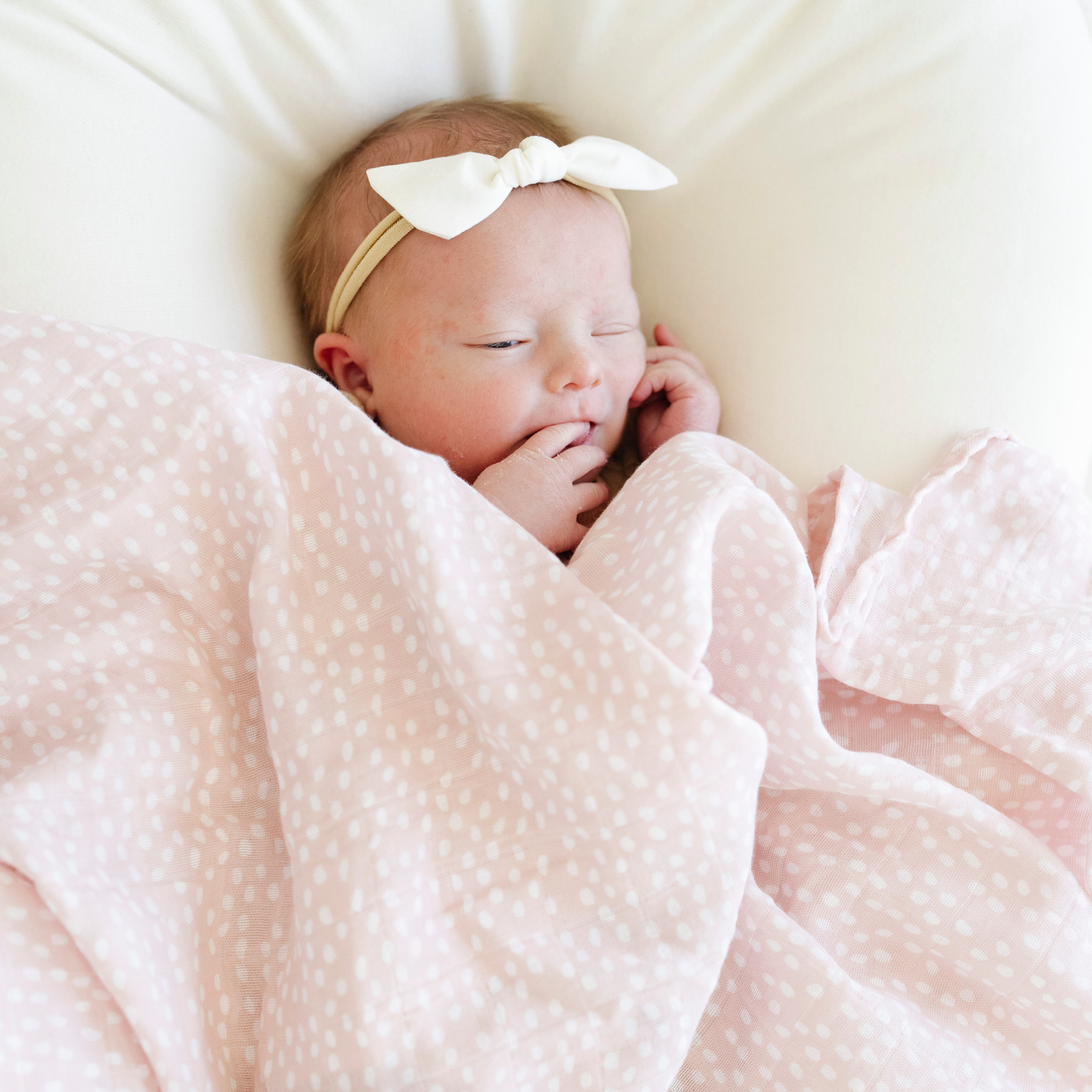 Baby girl snuggled with Saranoni Cotton Muslin Swaddle in Fallen Petal. 