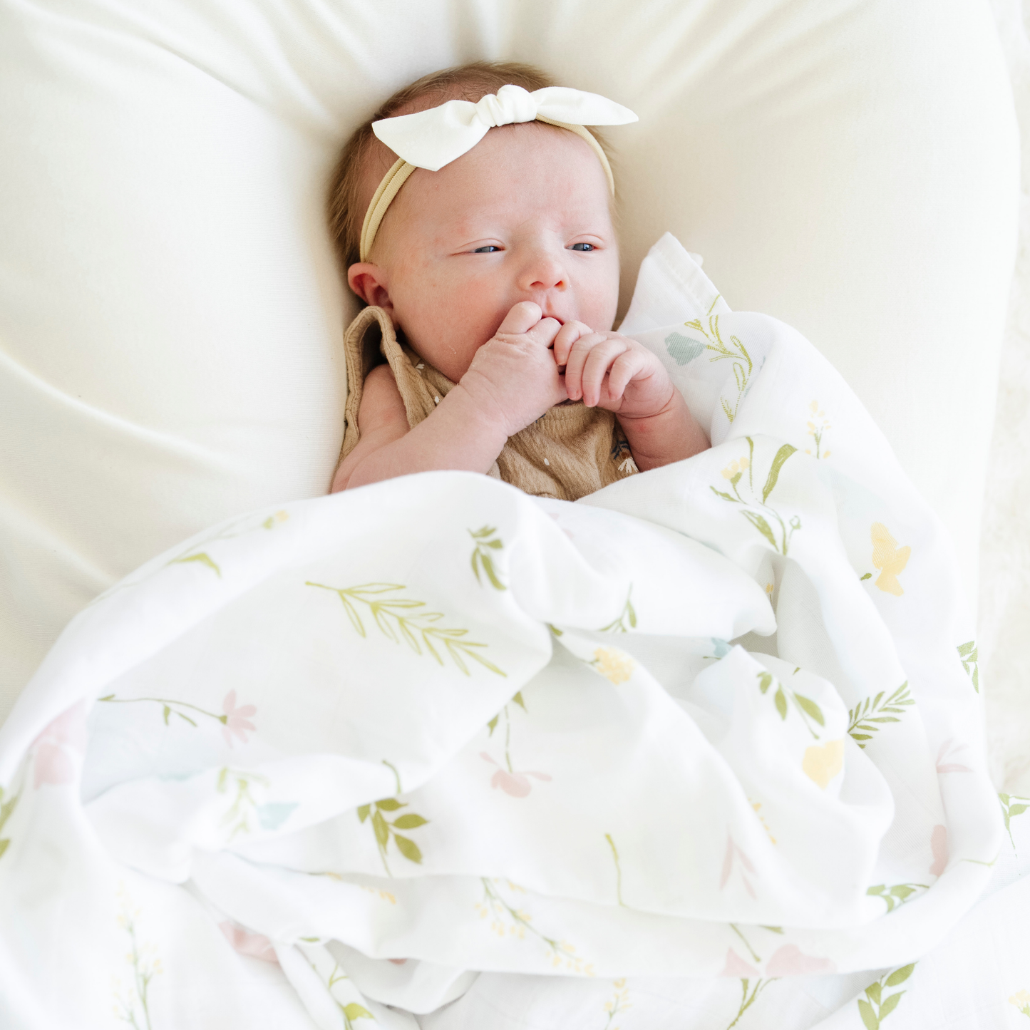 Baby girl snuggled with Saranoni Cotton Muslin Swaddle in Floral Fields. 