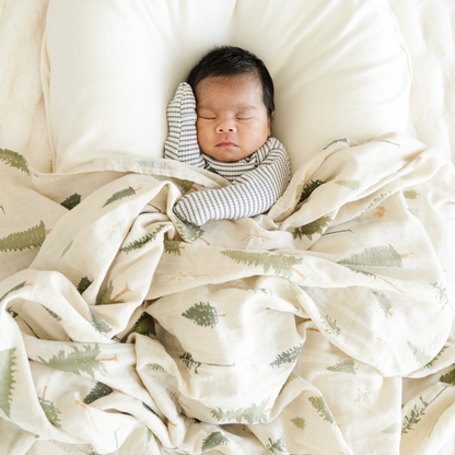 Baby boy snuggled with Saranoni soft Cotton Muslin Swaddle in Pine. 