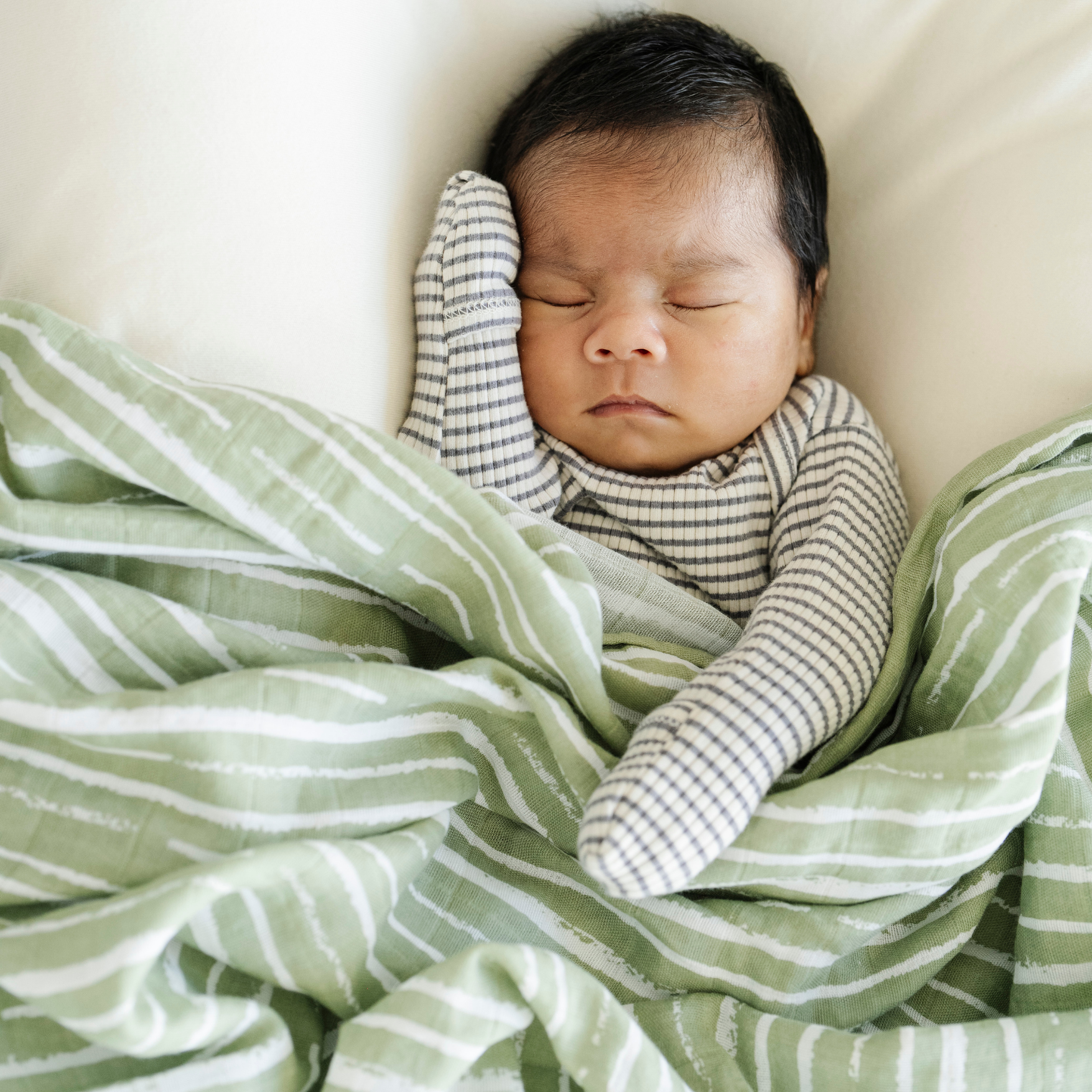 Baby boy snuggled with Forest Stripe Cotton Muslin Saranoni Swaddle. 