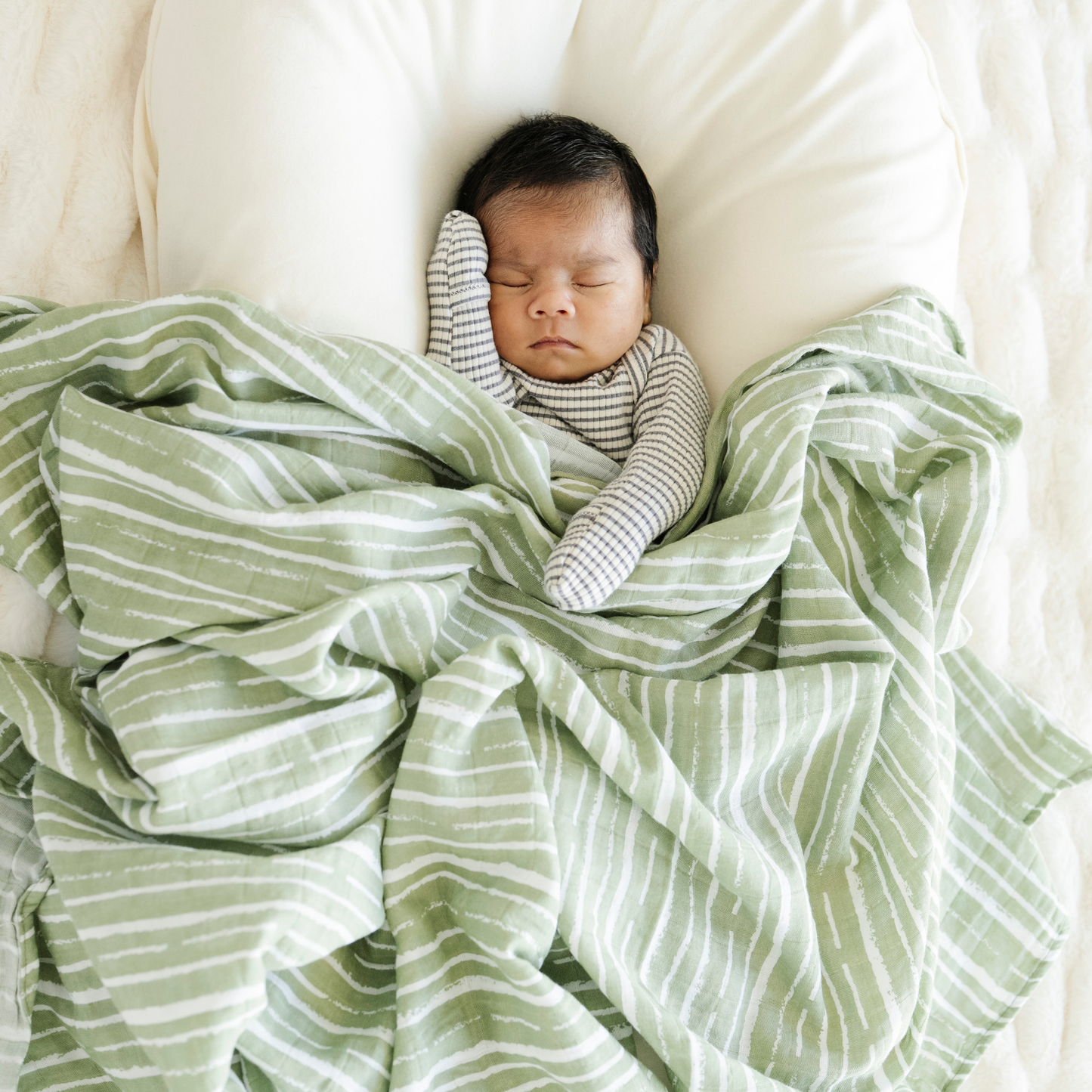 Baby boy snuggled with Saranoni soft Cotton Muslin Swaddle in Forest Stripe. 